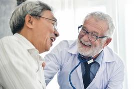 A man with glasses and a stethoscope around his neck is talking to another person.