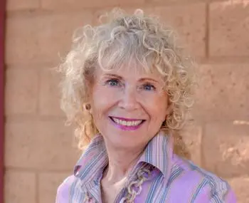 A woman with blonde hair and pink shirt smiling.